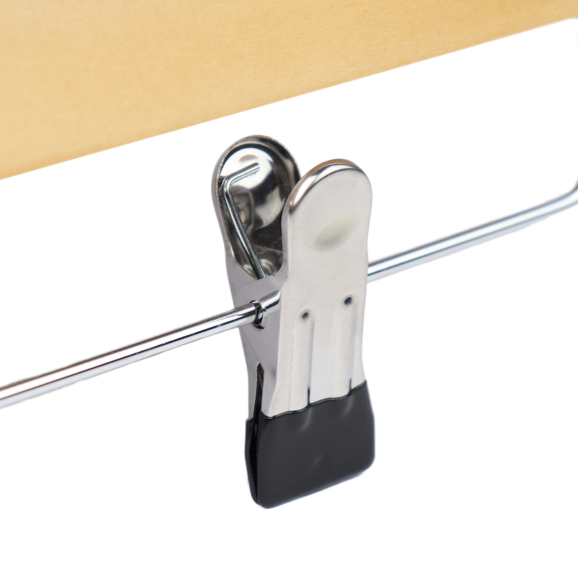 A close-up image of a metallic binder clip securing a stack of beige paper. The clip is attached to a shiny wire-like object and has black gripping pads on its ends, reminiscent of the premium wood used in **Rustic Motifs Natural Wooden Clip Bottom Hanger 35cm** for wardrobe organization.