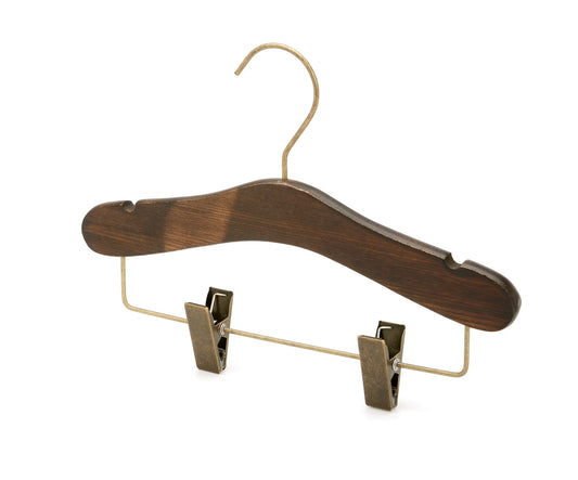 A Rustic Motifs Wooden Antique Kids Top Clip (Brass Hook) 28cm made from dark ash wood, featuring a metal hook and metal clips at the bottom. The hanger has notches on the shoulders for hanging straps and a horizontal bar with two adjustable clips, suitable for hanging kids' pants or skirts.