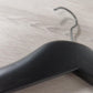 Close-up of a Rustic Motifs Wooden Black Jacket 39cm with a curved hook on a wooden surface. The hanger's smooth and curved design is clearly visible, and the wood grain of the surface adds texture to the background, making it perfect for an elegant jacket display.