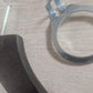 Close-up of a **Rustic Motifs Wooden Hotel Anti Theft Jacket (Dark Brown) 44cm** with a protruding screw on a wooden surface, accompanied by a round metal washer with tabs in a dark brown finish. The image focuses on the hardware components, suggesting construction or assembly work.