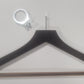 A Rustic Motifs Wooden Hotel Anti Theft Jacket (Dark Brown) 44cm is lying against a white background. Above the hanger is a metal ring-like object with a small bracket attached, emphasizing security priority for guests.