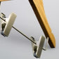 A Bamboo Wood Sustainable Children's Top Clip Hanger 26cm by Rustic Motifs is shown against a plain, light background. The eco-friendly hanger is angled slightly and designed to hold clothing items such as skirts or pants.