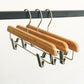 Three Rustic Motifs Bamboo Wood Sustainable Clip Bottom Hanger 35cm are hanging from a black metal rail. The background is plain white, showcasing these eco-friendly wardrobe accessories.