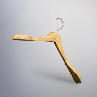A Rustic Motifs Bamboo Wood Sustainable Top Jacket Hanger 42cm with a curved design and metal hook is suspended against a plain, light gray background, perfect for eco-friendly clothing organization.