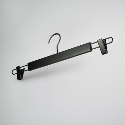 A Rustic Motifs Black Wooden Clip Bottom Hanger 37cm with two sturdy, adjustable clips, designed for hanging pants or skirts. The Rustic Motifs hanger features a hook at the top that offers 360-degree rotation for easy positioning on any rod or bar. It rests against a plain, light grey background.