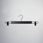A Rustic Motifs Black Wooden Clip Bottom Hanger 37cm is centered against a plain, light-colored background. The hanger features a curved hook at the top that allows for 360 degree rotation, a straight bar in the middle, and metal clip extensions on either side to hold clothing securely.