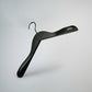 A stylish, black wooden jacket top coat hanger with a hook at the top is suspended against a white background. The Black Wooden Jacket Top Coat Hanger 38cm by Rustic Motifs features broad, angled shoulders designed to support heavier garments without slipping off, showcasing high-quality craftsmanship.
