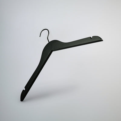 A Black Wooden Top Clothes Hanger with Notch 44cm by Rustic Motifs is suspended against a minimalist, light gray background. This top-notch clothing storage solution features a standard hook at the top and angled arms with shoulder notches for securing garments.