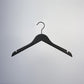 A Black Wooden Top Clothes Hanger with Notch 38cm by Rustic Motifs is hanging against a white background. The metal hook on top is centered.