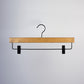 A Dark Wood Sustainable Bottom Trouser Skirt Hanger With Clips 37cm from Rustic Motifs, featuring a metal hook and bar. The hanger includes two adjustable black plastic clips on either end of the metal bar for securing clothing items. The background is plain white.