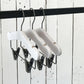 Three Rustic Motifs White Ash Wood Coat Kids Hanger with Bar 28cm are suspended from a black metal rod. The background features vertical white wooden planks.