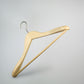 A **Rustic Motifs Natural Wooden Jacket Hanger with Trouser Bar 44cm** with a silver metal hook, designed for hanging clothes. This high-quality hanger features a smooth, natural wood finish and a contoured shape suitable for shirts, jackets, or dresses. The background is plain and light grey, emphasizing the simplicity of the design.