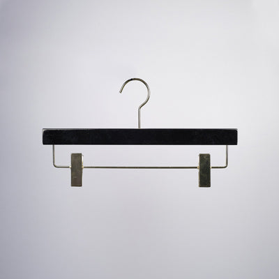 A Luxury Black Wooden Clip Bottom Premium Hanger 35cm from Rustic Motifs, made of high-quality black wood, featuring metal clips and a hook for hanging, is centered against a plain white background.