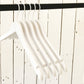 Five Rustic Motifs White Wooden Clothes Hangers with Notch 38cm are hanging from a black horizontal rod. The background consists of a white wooden wall with visible seams and nail heads, adding a rustic touch to the otherwise minimalistic scene, highlighting effective closet organization.