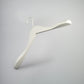 A white wooden jacket top coat hanger 44cm from Rustic Motifs is isolated against a plain gray background. Mimicking the style of a White Wooden Jacket Top Coat Hanger 44cm, it has a broad, contoured shape designed to maintain the structure of garments.