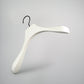 A sleek, modern White Wooden Jacket Top Coat Hanger 38cm by Rustic Motifs with a curved design and wide shoulders is depicted against a plain grey background. It features a black hook for hanging, making it perfect for use as a jacket hanger.